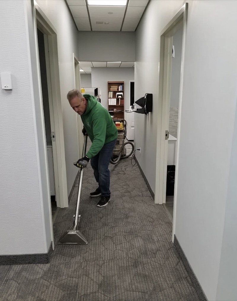 Bespoke Cleaners team member cleaning building hallway carpet